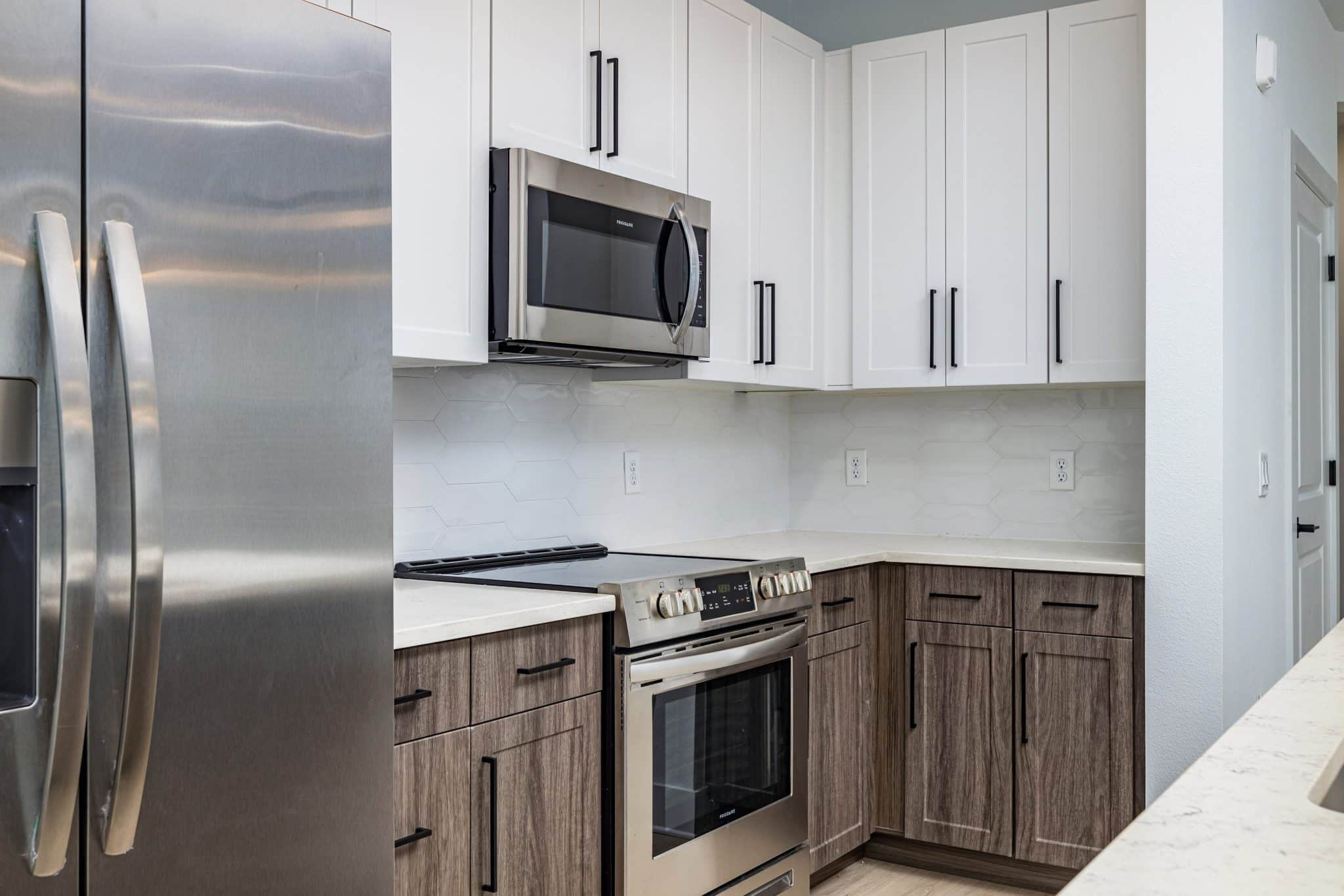 A kitchen corner with stainless steel appliances, quartz countertops, and two-toned cabinetry at Ridley at Waterset.