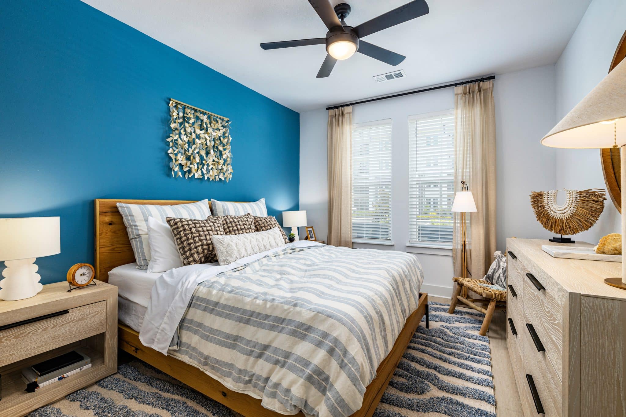 A furnished apartment bedroom with two windows and a ceiling fan at Ridley at Waterset.