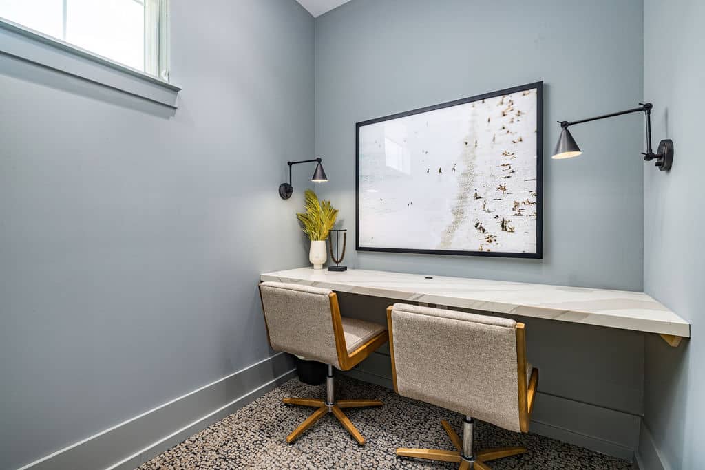 A business center with a window, a built-in desk, and two chairs at Ridley at Waterset.