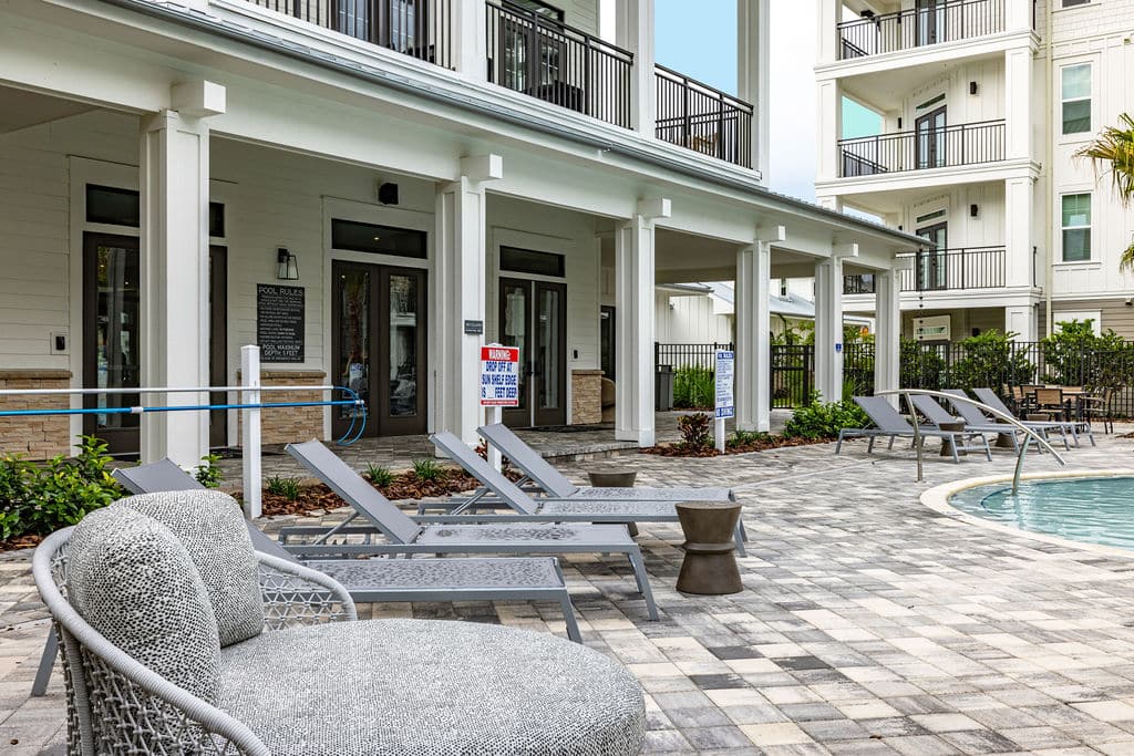 Lounge chairs on a sundeck near a resort-style pool and a community clubhouse at Ridley at Waterset.