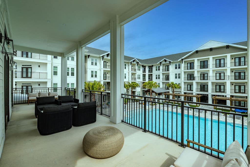 A clubhouse balcony with comfortable seating and a beautiful view of the pool at Ridley at Waterset.