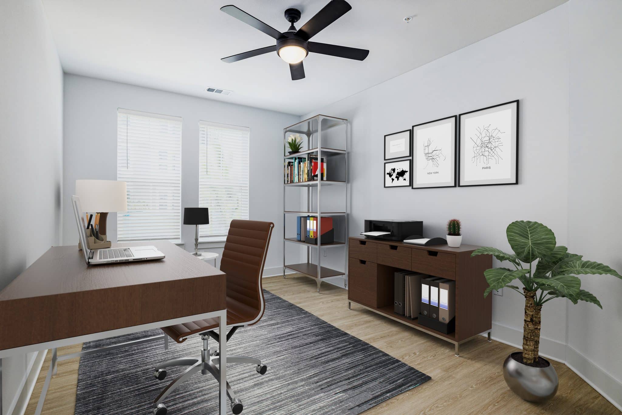 An apartment home office with two windows, a ceiling fan, and hardwood-style flooring at Ridley at Waterset.